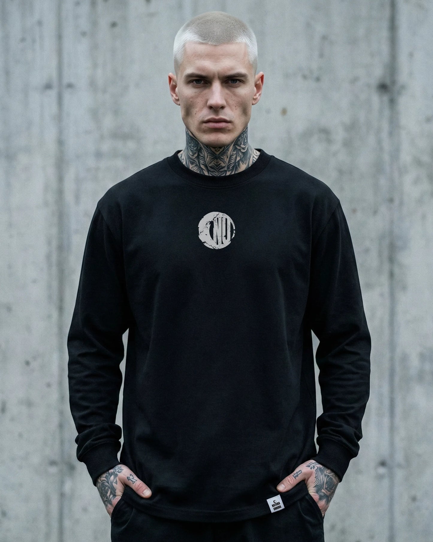 Männliches Model trägt Stanley/Stella Freestyler Longsleeve T-Shirt in Schwarz mit "Natura Umbra" Frontprint – nachhaltige Unisex Streetwear.