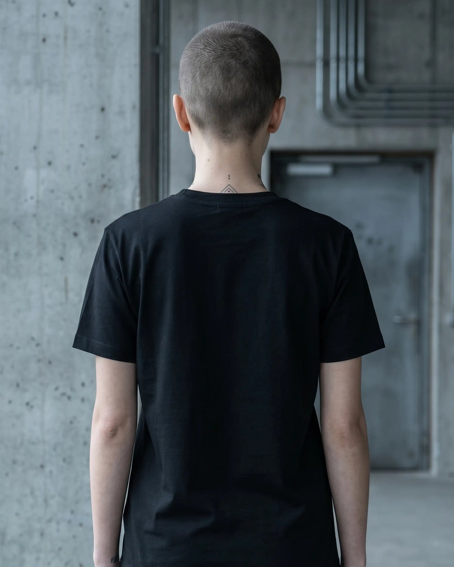 Weibliches Model mit schwarzem Stanley/Stella Crafter T-Shirt – Back, nachhaltig produziert aus Bio-Baumwolle, Label Natura Umbra.