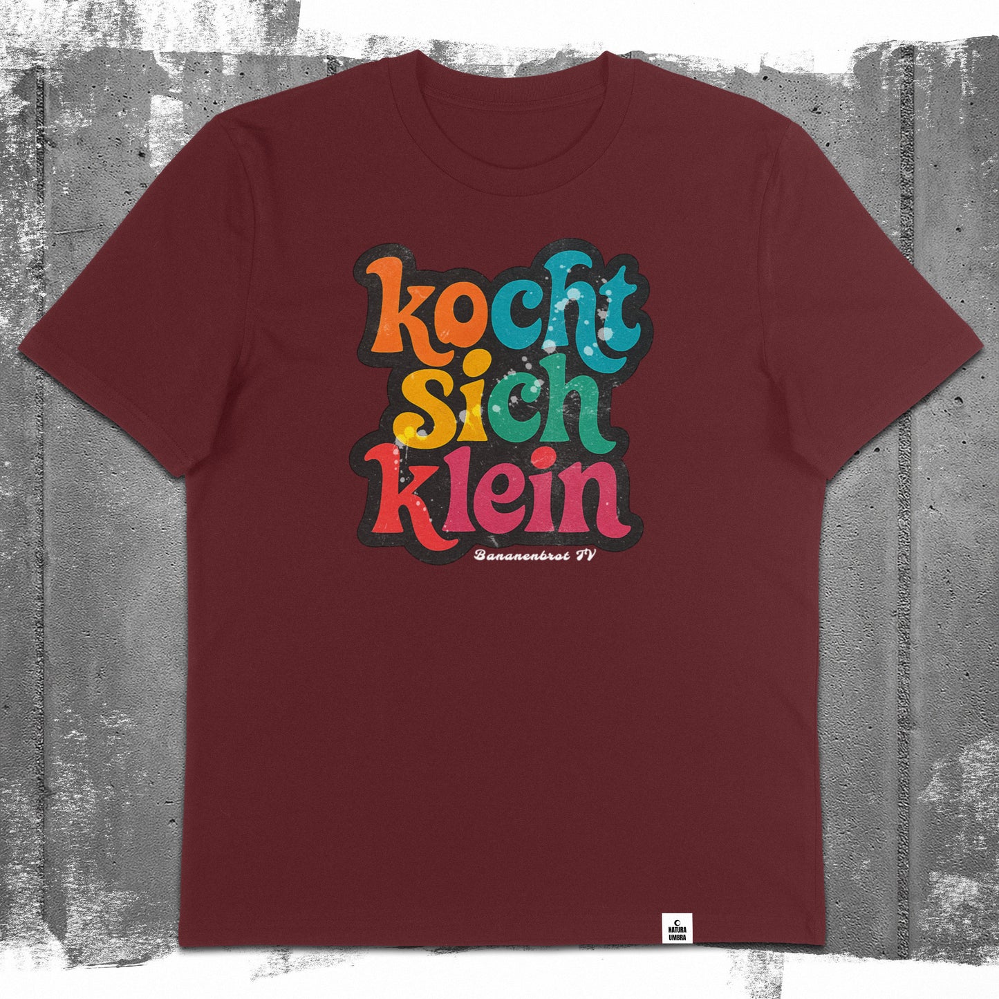 Flatlay des Unisex T-Shirts „Kocht sich klein“ in der Farbe Burgundy – Stanley/Stella Creator 2.0 von Natura Umbra mit Frontprint.