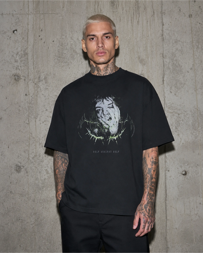 Model trägt schwarzes SELF AGAINST SELF Oversized T-Shirt vor einer Betonwand.