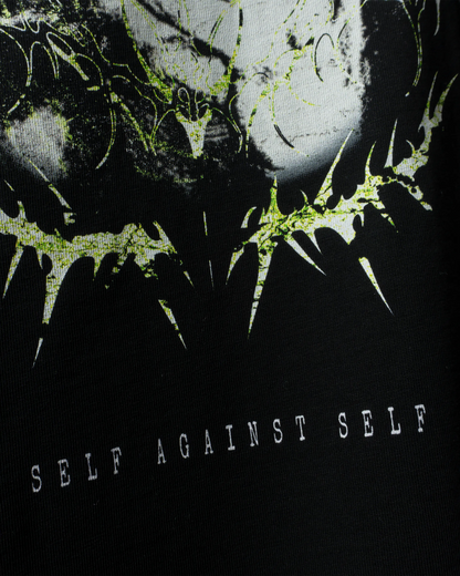 Detailaufnahme des „Self Against Self“-Drucks in Schwarz, Weiß und Neongrün auf schwarzem T-Shirt-Stoff.
